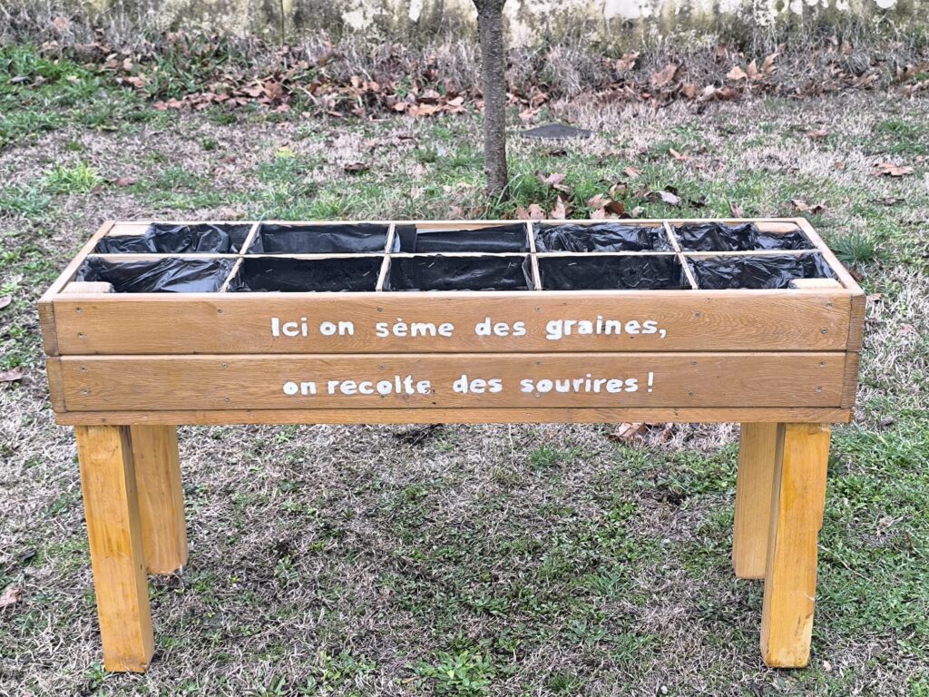 photo d'une jardinière en bois avec écrit "Ici on sème des graines, on récolte les sourires"